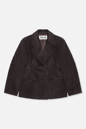Front view of a dark brown coat with wide notched lapels, a concealed front closure, welt pockets and gathered sleeve details.