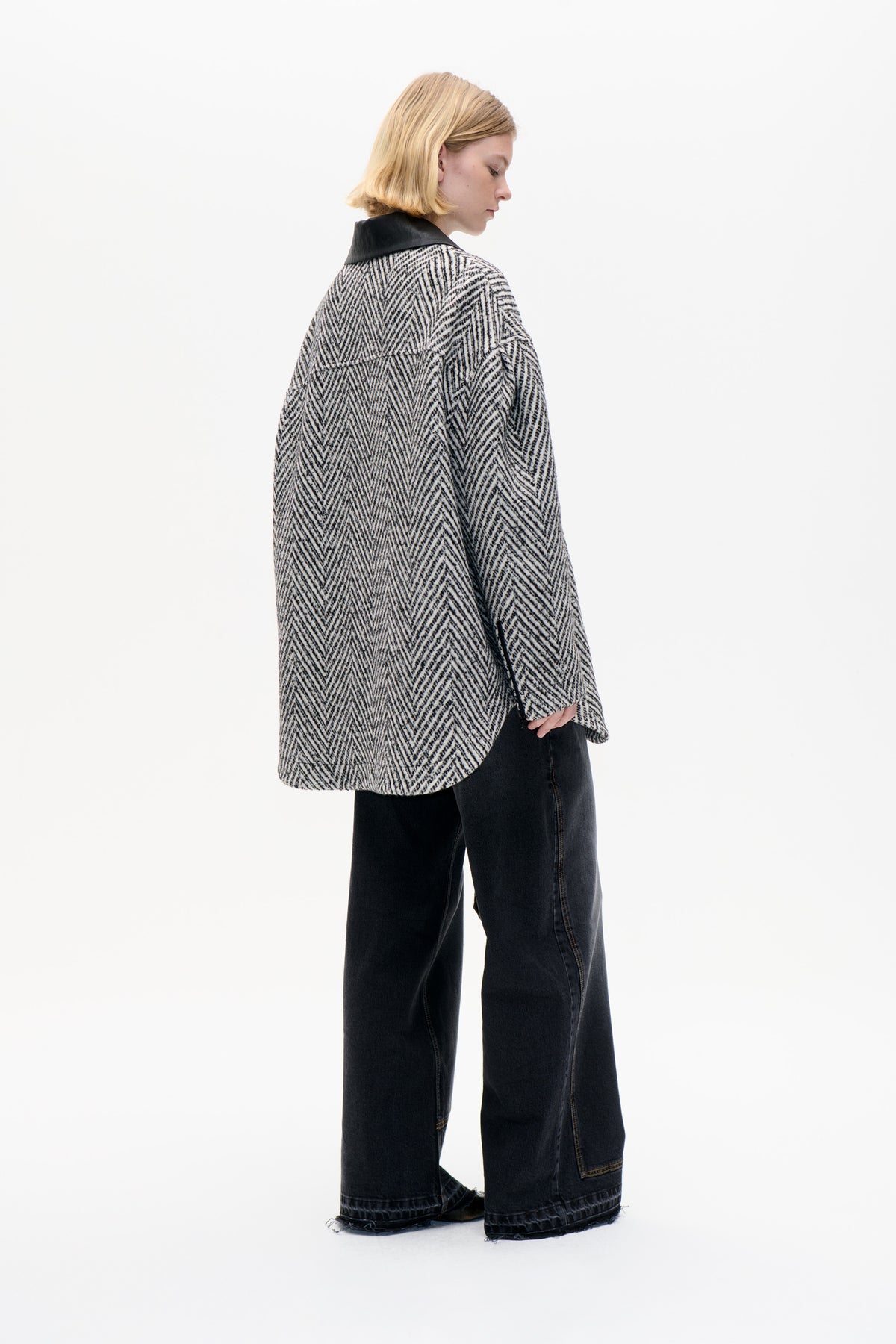Model wearing an oversized black-and-cream patterned jacket with a contrasting black collar, shown from the side and back.