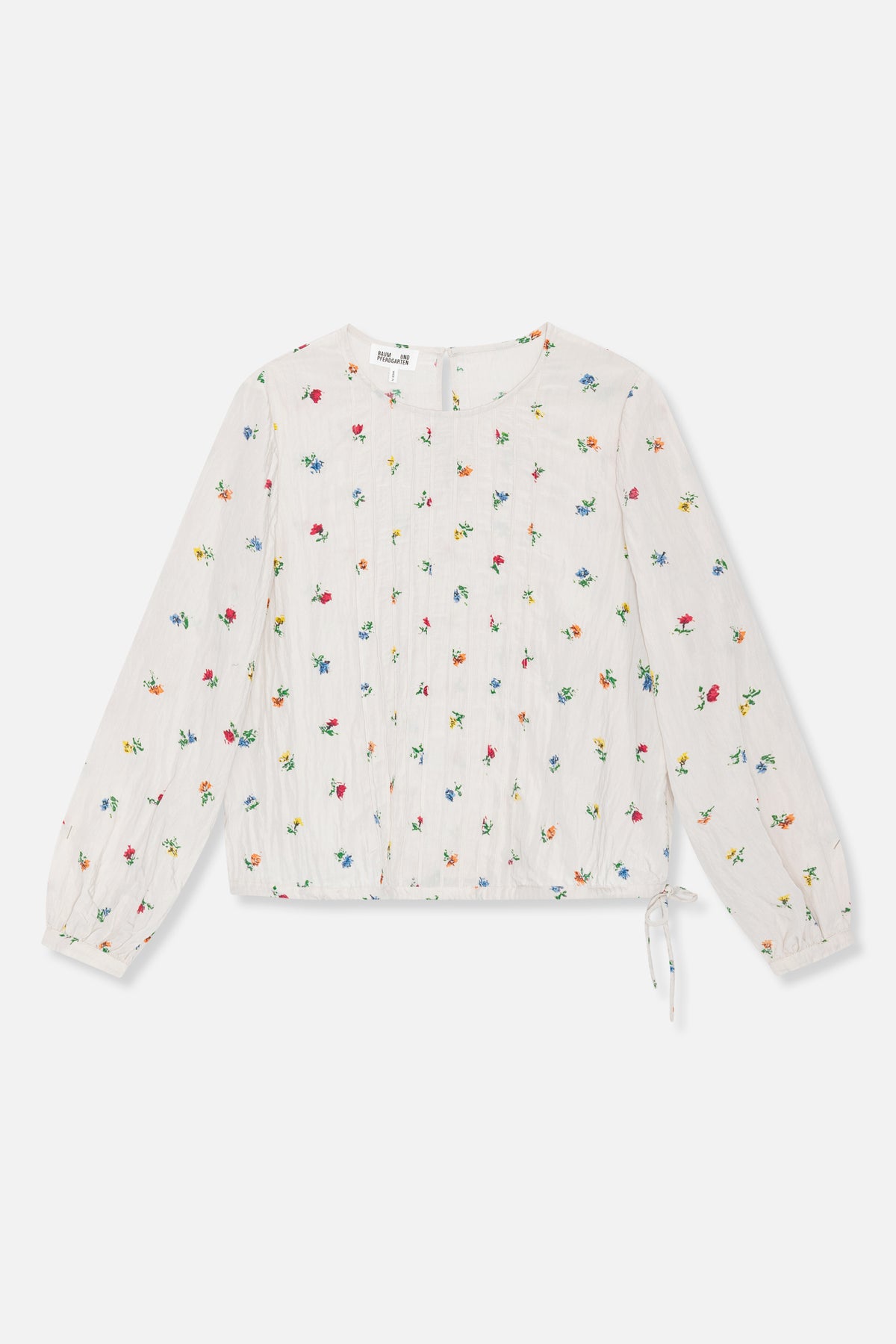 Front view of an ivory long-sleeved blouse with scattered multicolour flowers, vertical pintuck detailing and a tie at the hem.