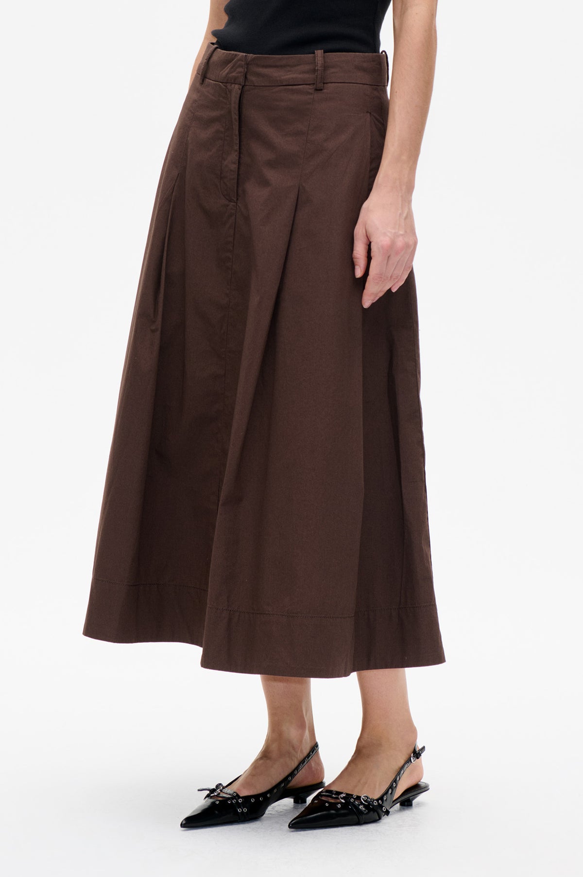 Close front view of a dark brown flared skirt with a waistband, belt loops, vertical panel seams and a below-knee hem.