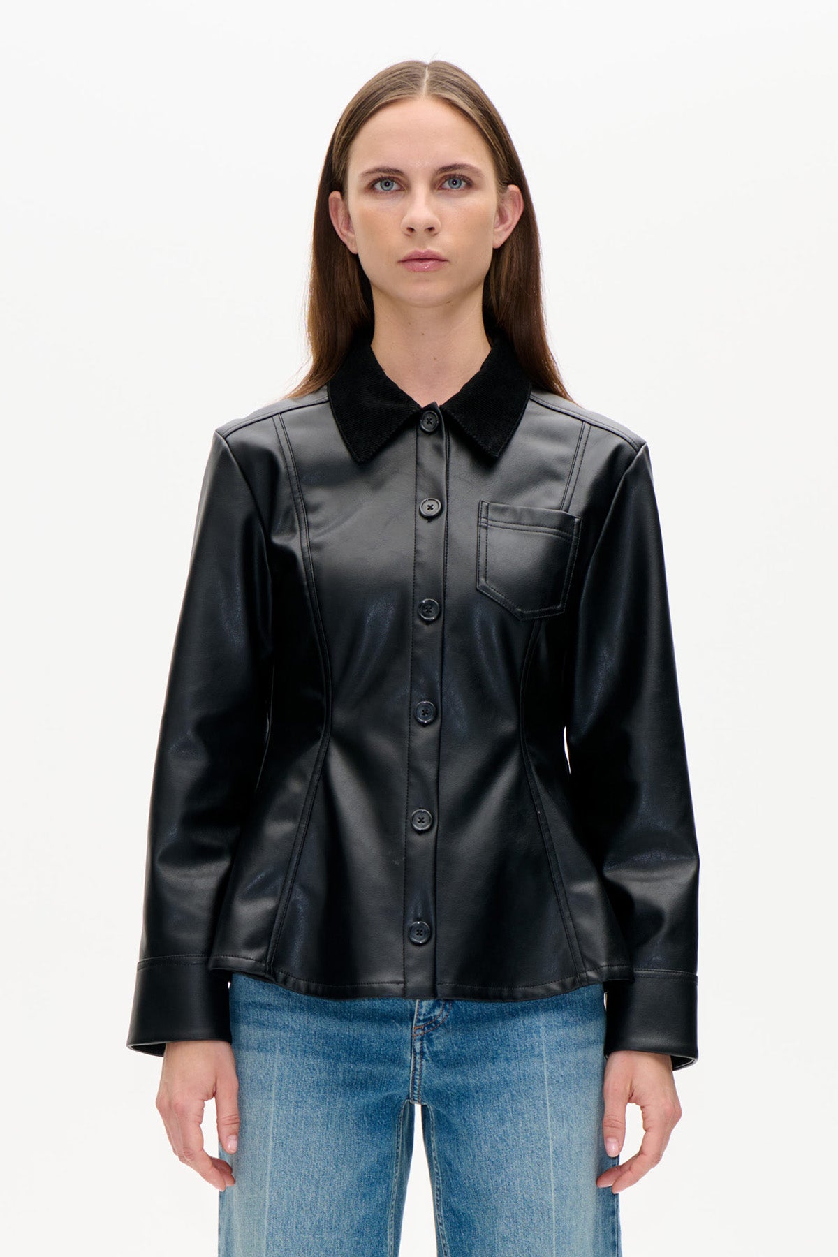 Vue de face d'une veste noire boutonnée sur le devant, col contrastant, coutures courbes et poche poitrine, portée avec un jean bleu.
