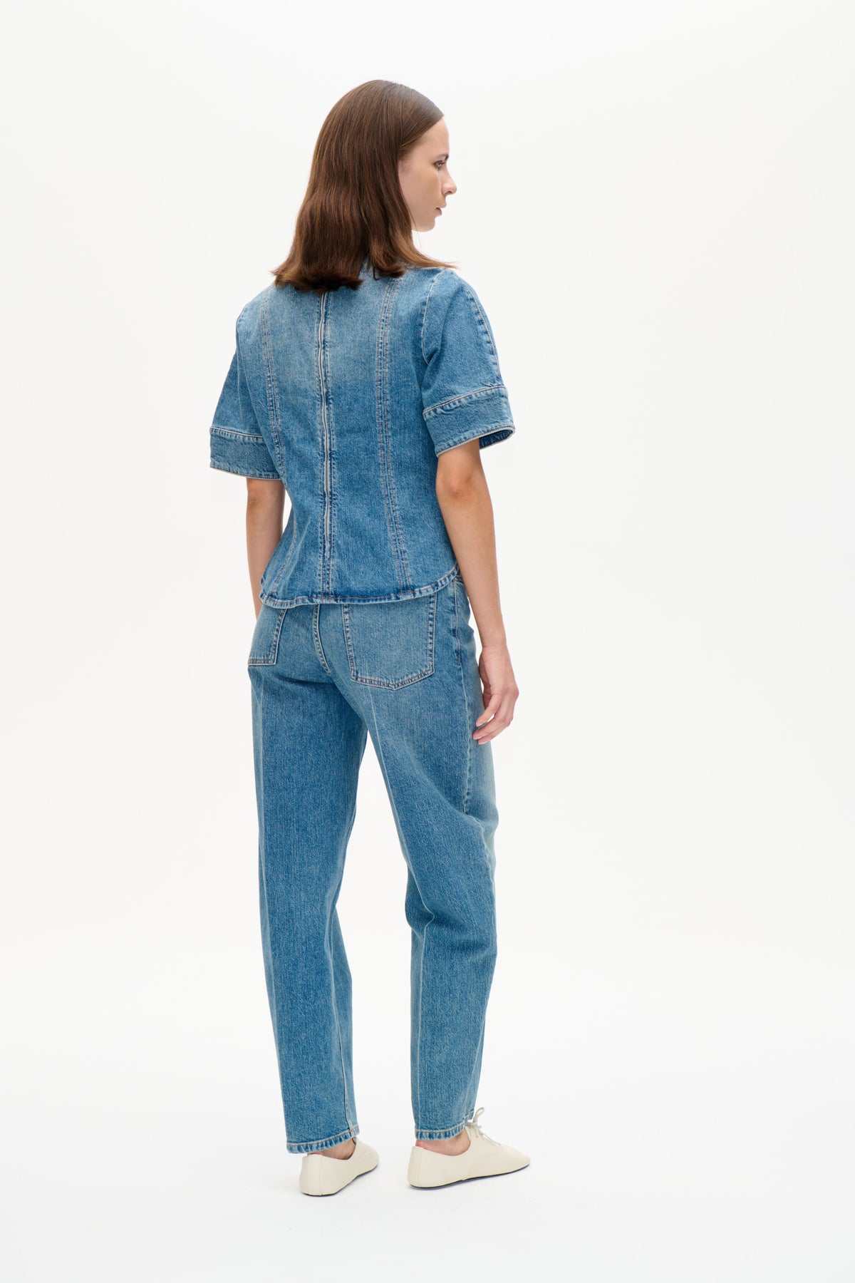 Mannequin portant un haut en denim bleu à manches courtes et un jean assorti, vu de dos et de côté sur fond blanc.