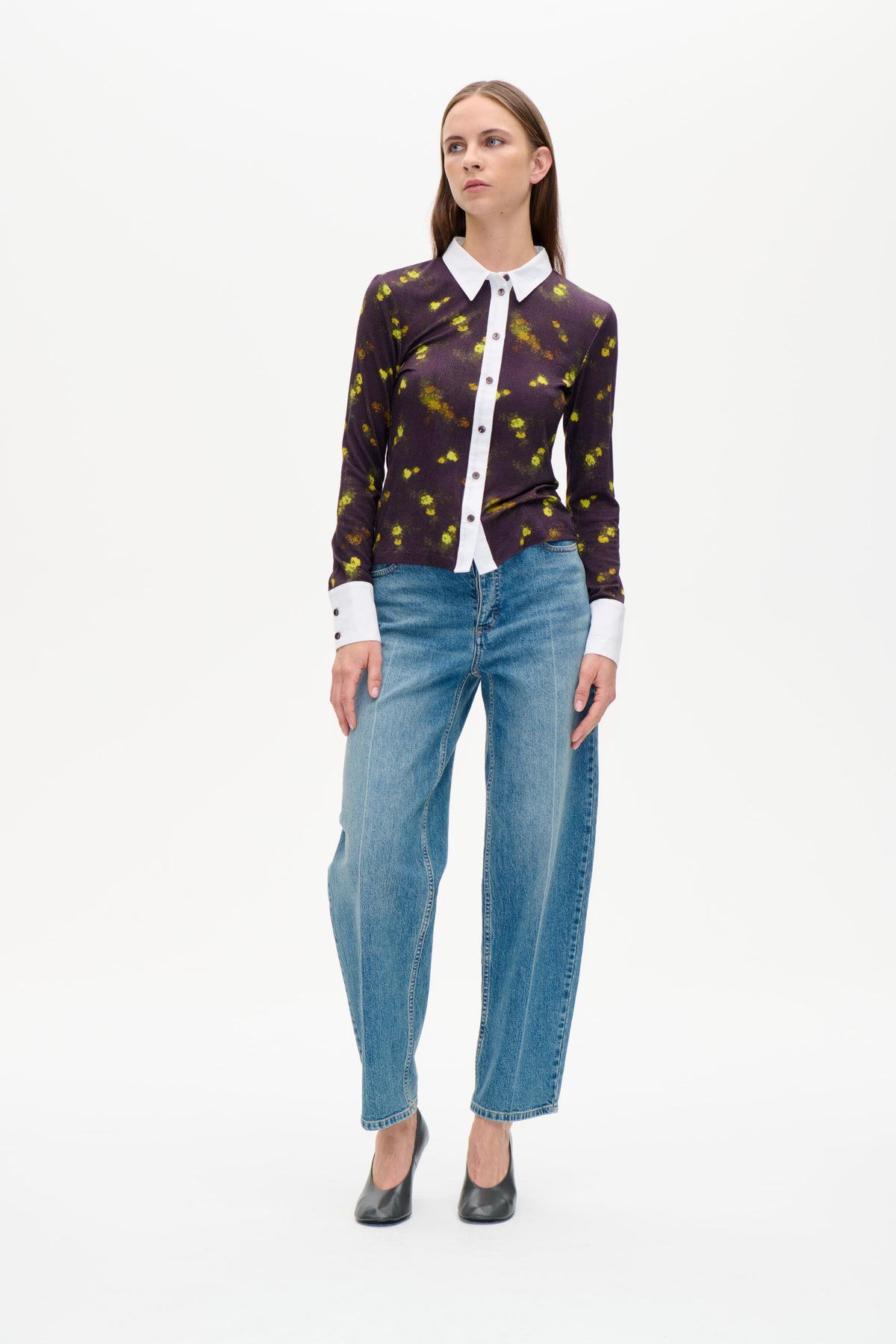 Front view of a dark purple long-sleeved button-front shirt with yellow floral motifs, white collar, placket and cuffs, worn with blue jeans.