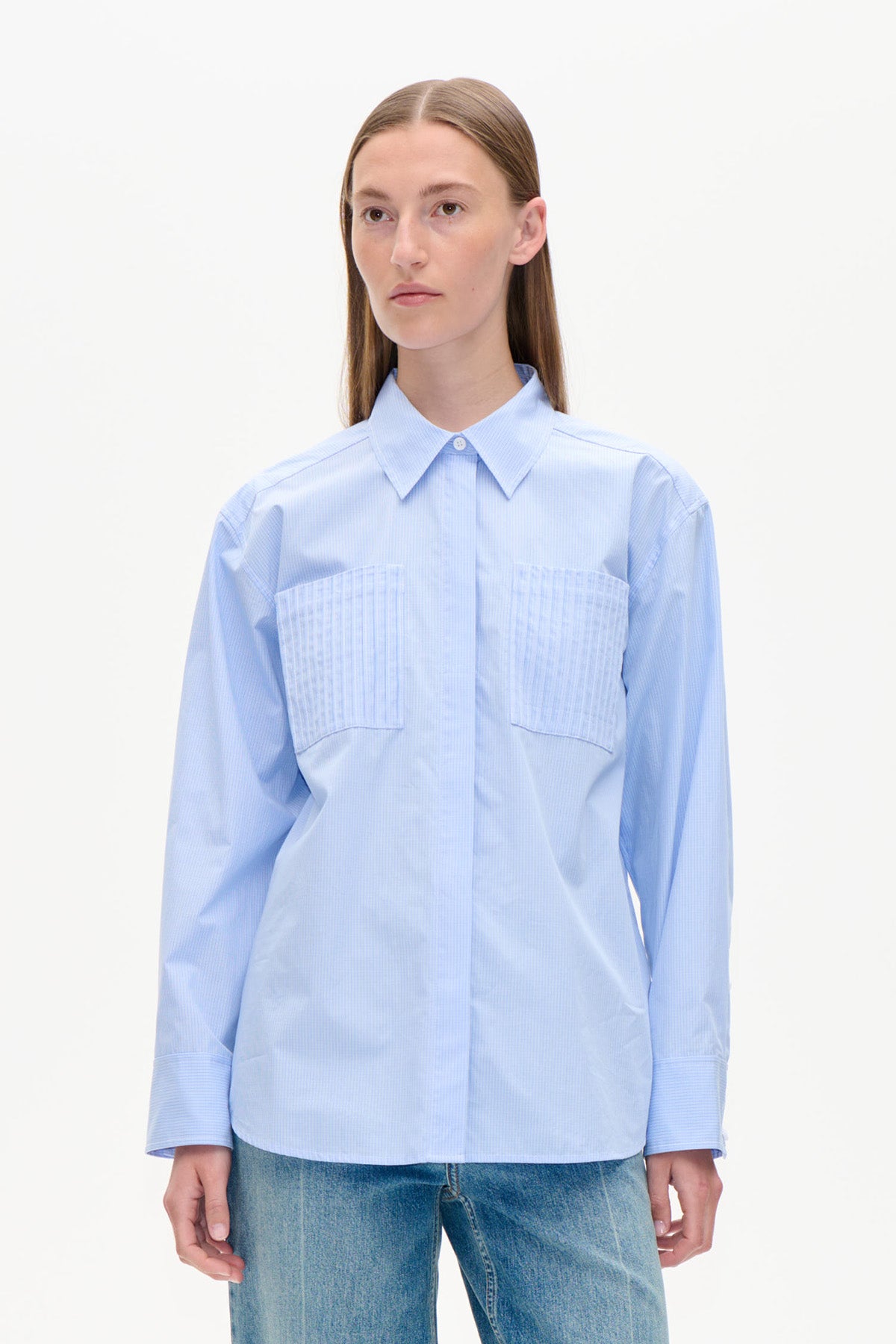 Front view of a light blue long-sleeved shirt with a pointed collar, concealed button placket and two pleated chest pockets.