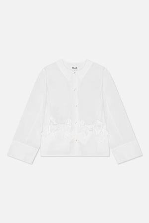 Vue de face d'une blouse blanche à manches longues, encolure ronde, boutons brillants, poignets larges et nœuds oversize à la taille.