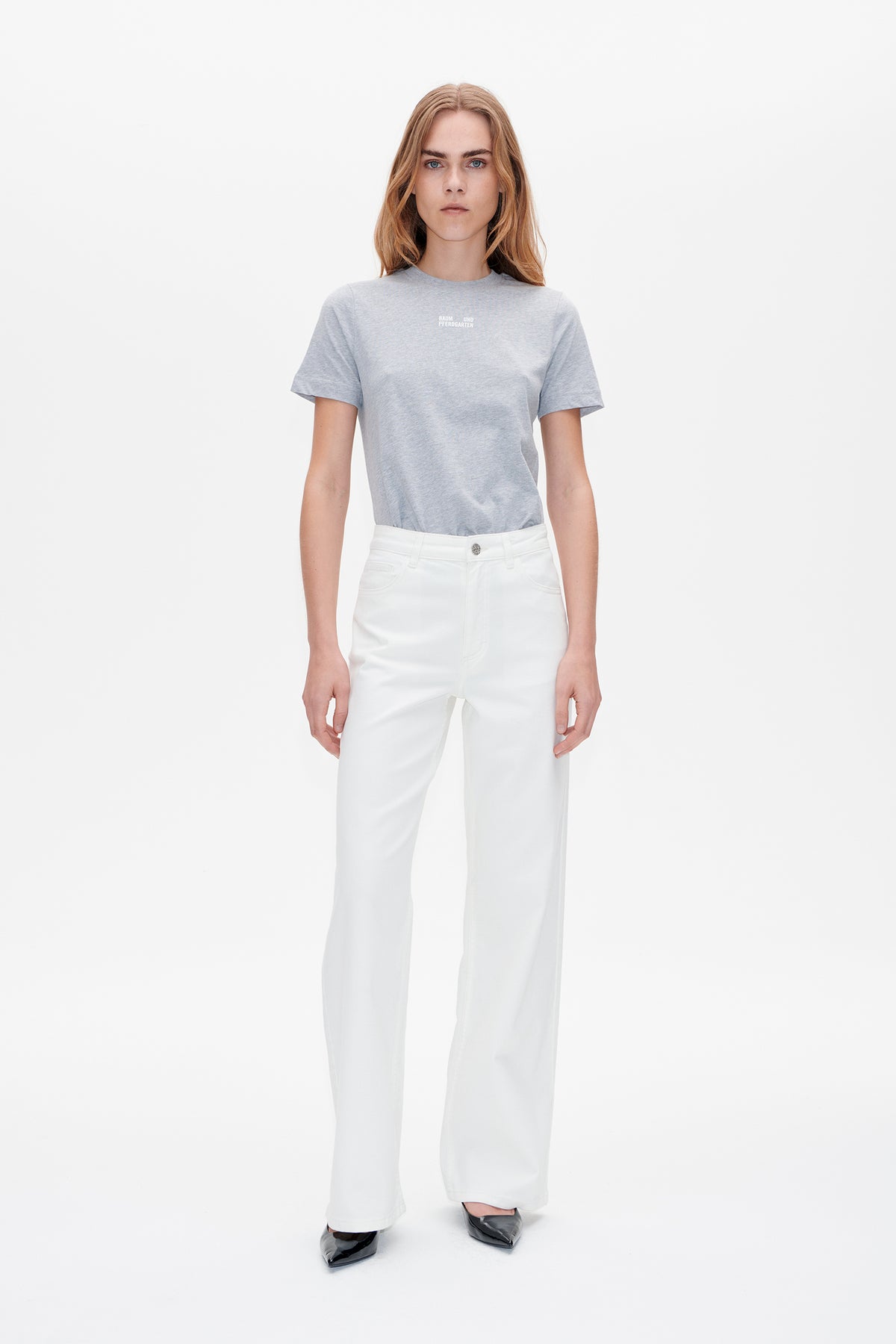 Front view of a model wearing a light grey short-sleeved T-shirt with a small white chest logo and white wide-leg trousers.