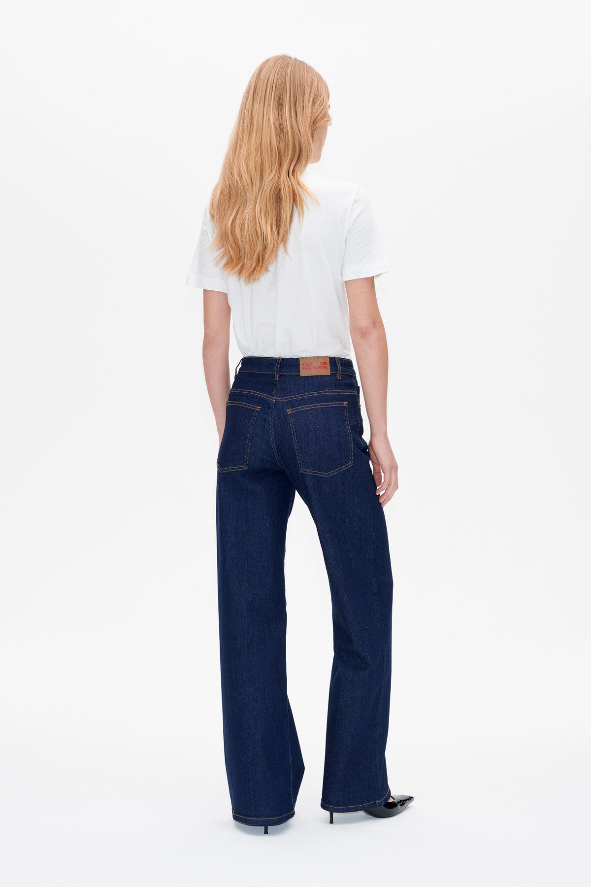 Back view of dark indigo wide-leg jeans with contrast stitching and patch pockets, worn with a white short-sleeve T-shirt.