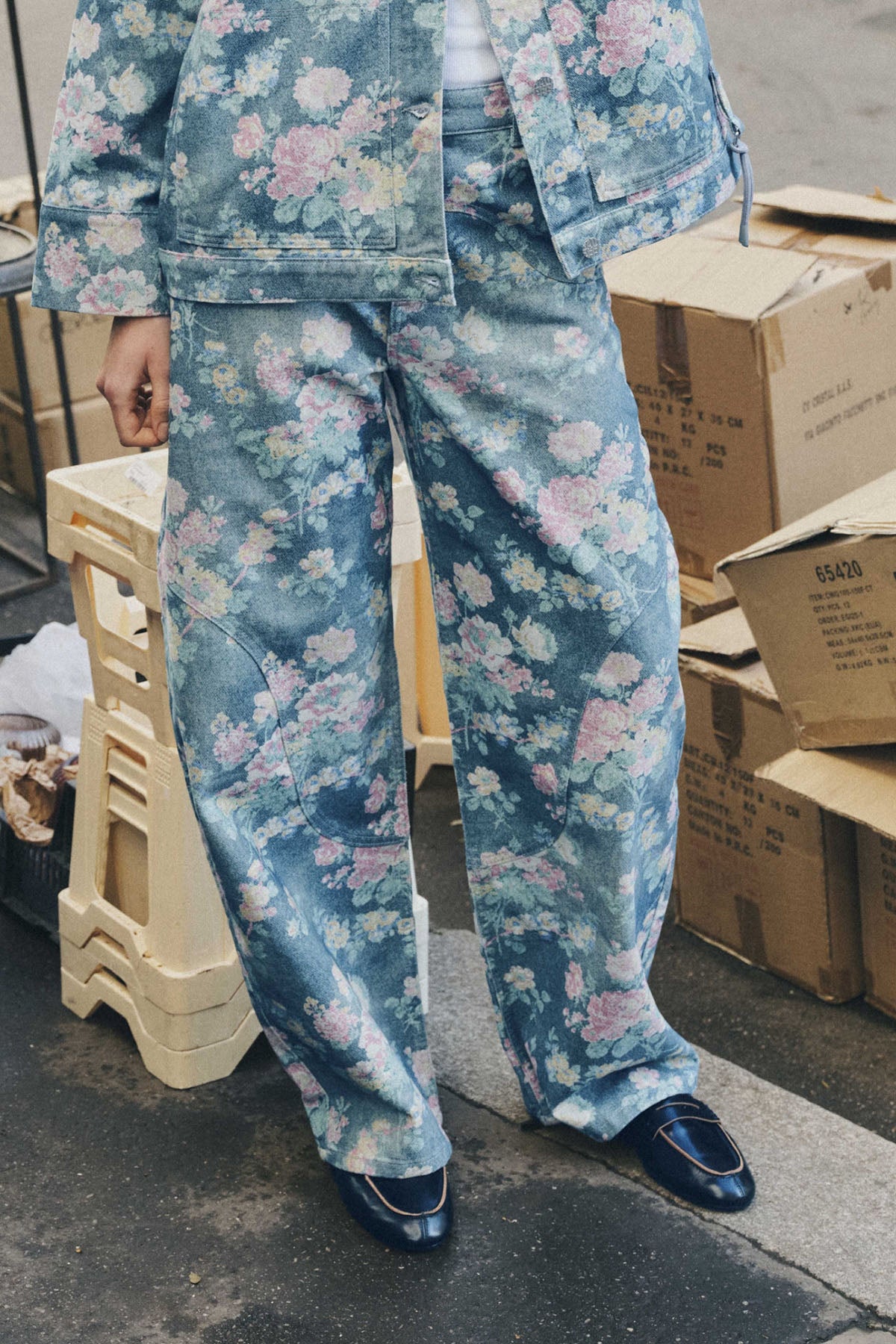 Close-up of a blue denim jacket and wide-leg jeans with a pink, cream and green floral print.