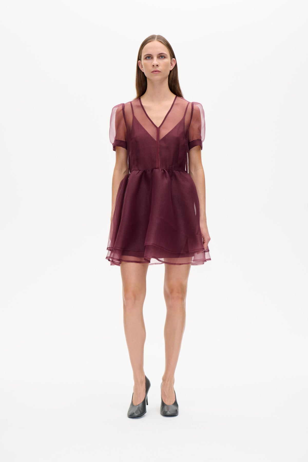 Front view of a plum short dress with sheer puff sleeves, a V-neckline, fitted waist and layered sheer hem