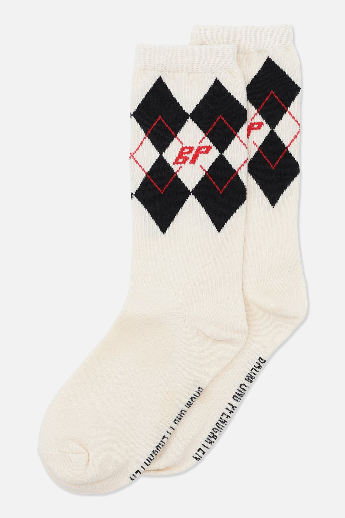 Pair of cream crew socks with black argyle diamonds, thin red diamond outlines and a red monogram near the cuffs.